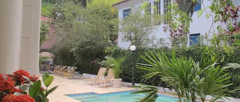 A pool area with lounge chairs and a building in the background.