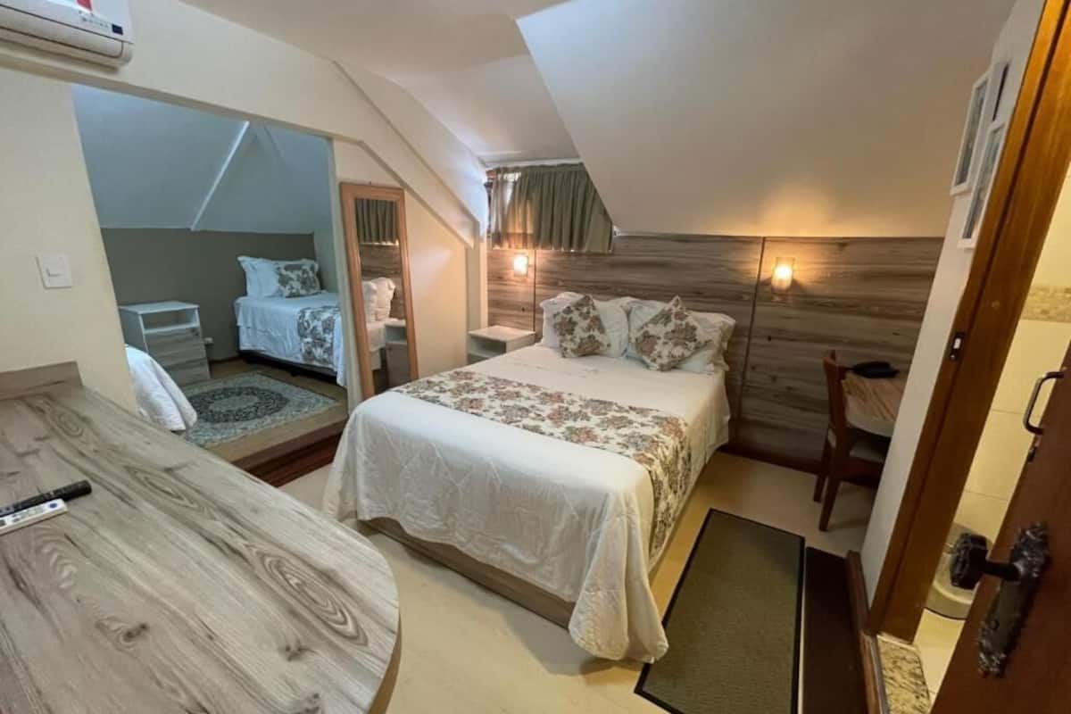 Quarto com cama, mesas de cabeceira, escrivaninha e espelho.