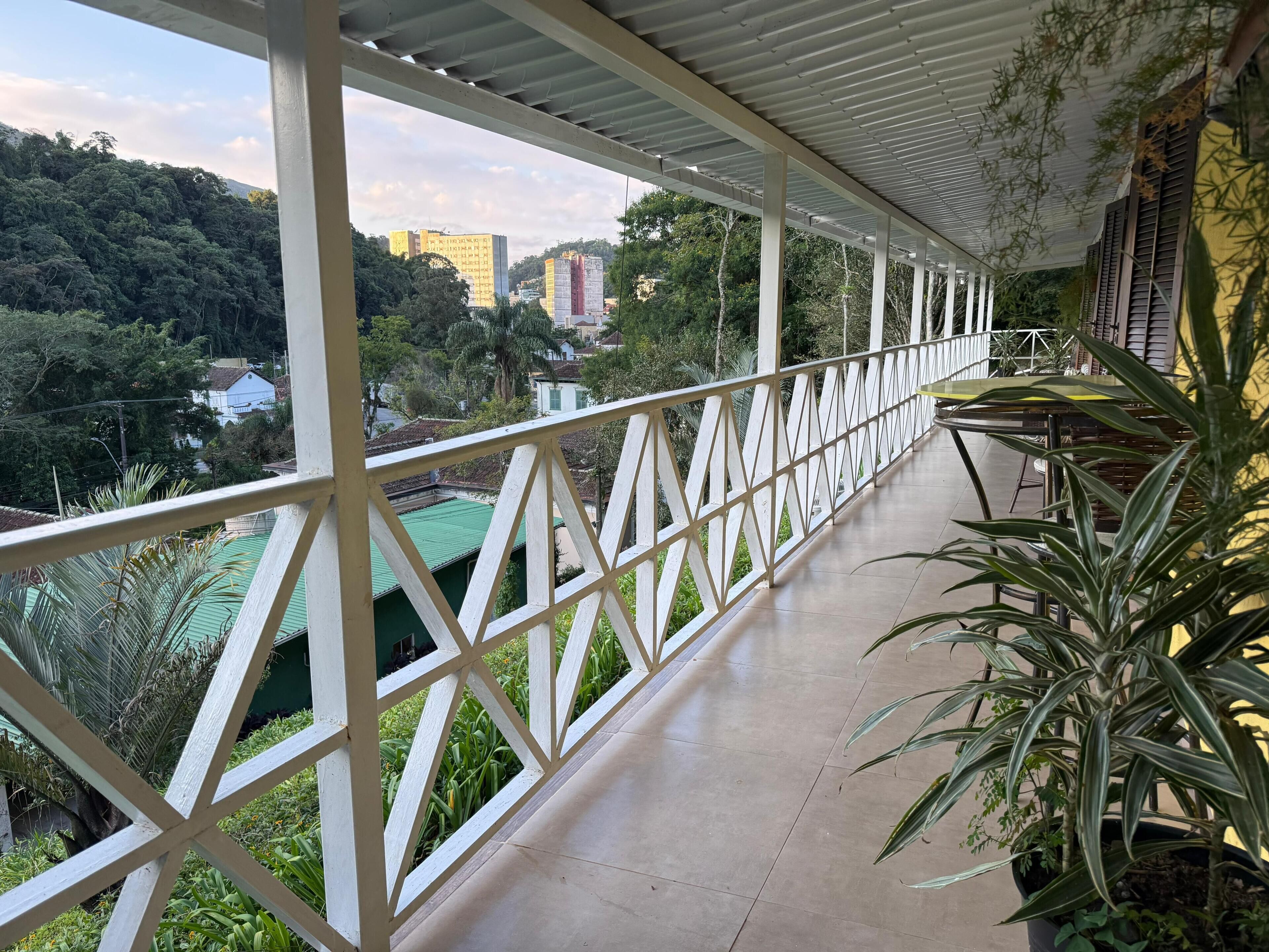 A covered balcony with a view of a cityscape and greenery.
