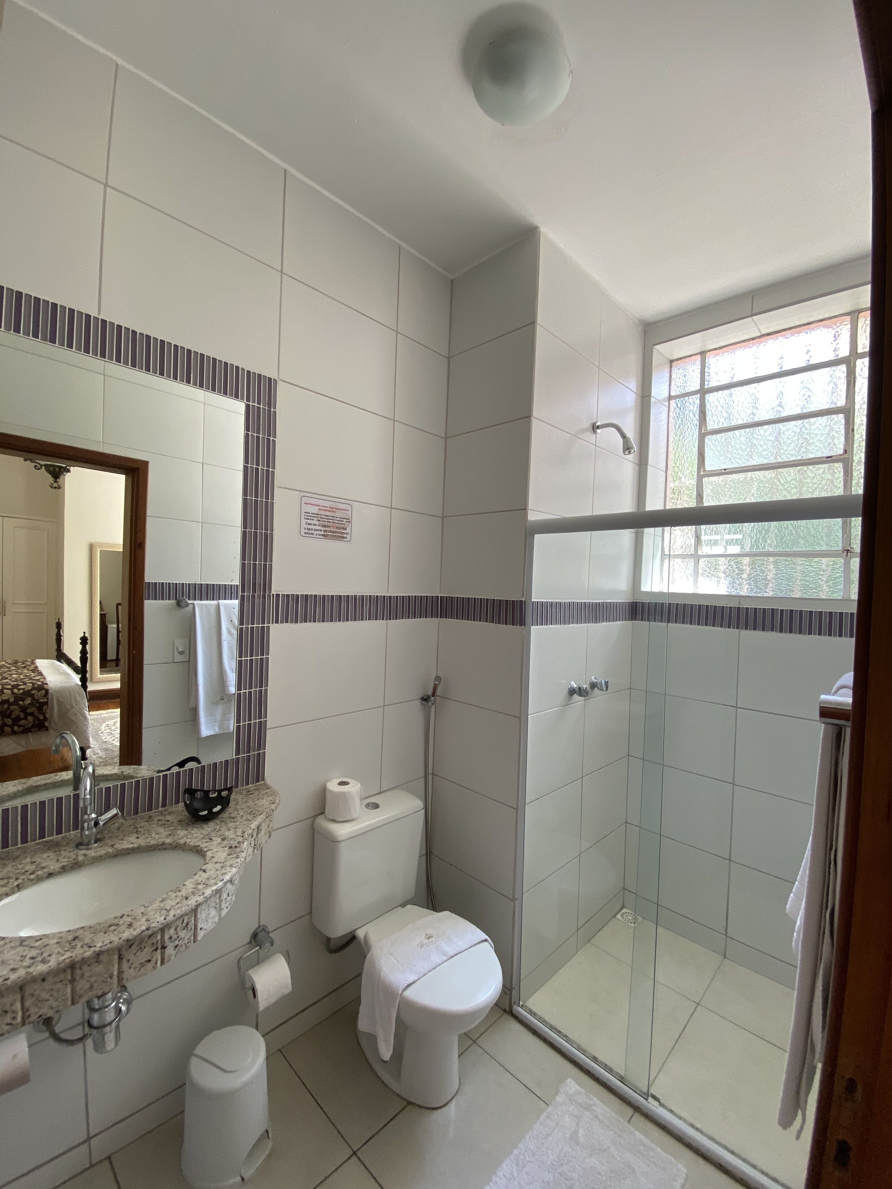 A bathroom with a shower, toilet, sink, and a mirror.