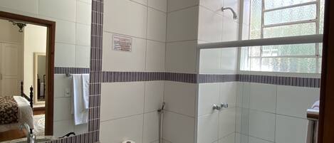 A bathroom with a shower, toilet, sink, and a mirror.