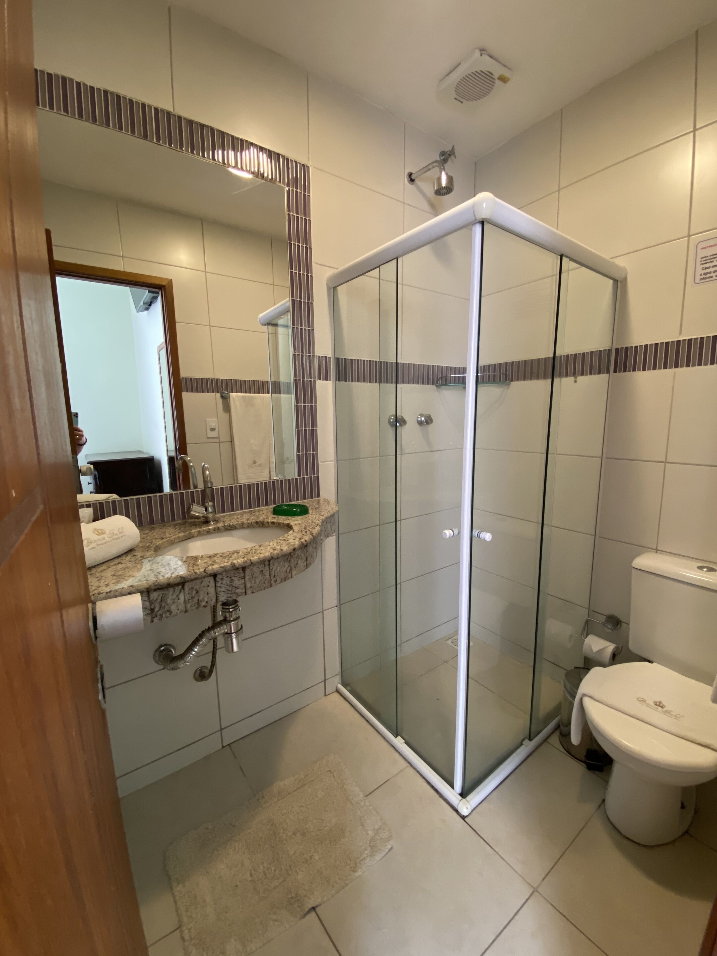 A modern bathroom with a glass-enclosed shower, a granite countertop sink, and a toilet.