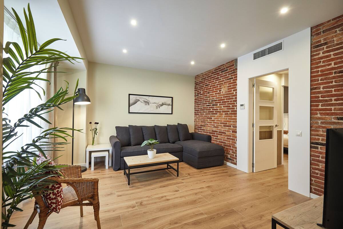 A modern living room with a sectional sofa, a coffee table, and a potted plant.