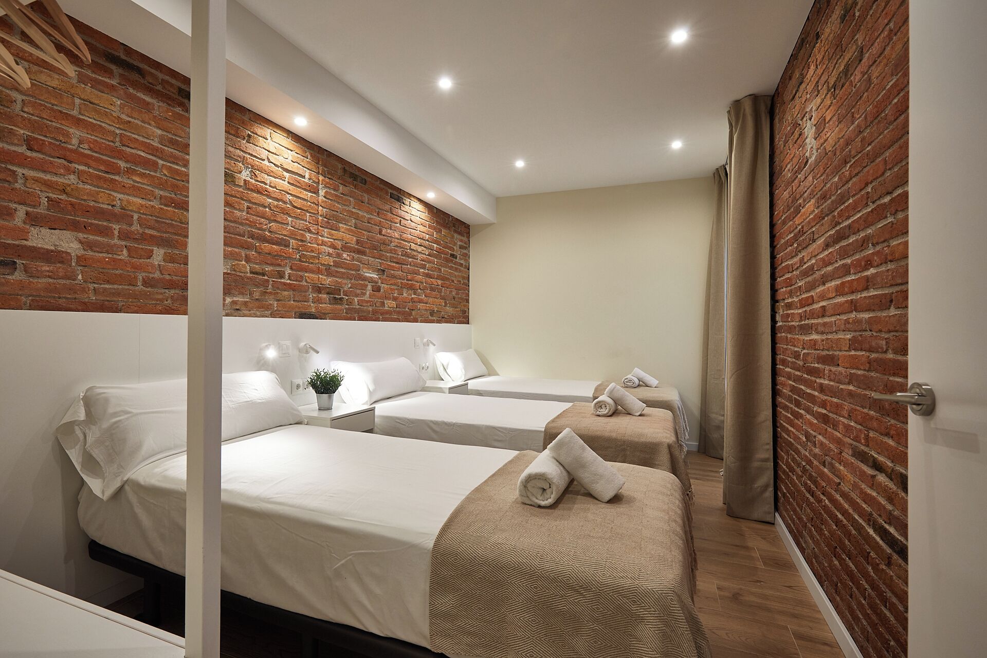 Een hotelkamer met twee bedden, een bakstenen muur en een houten vloer.