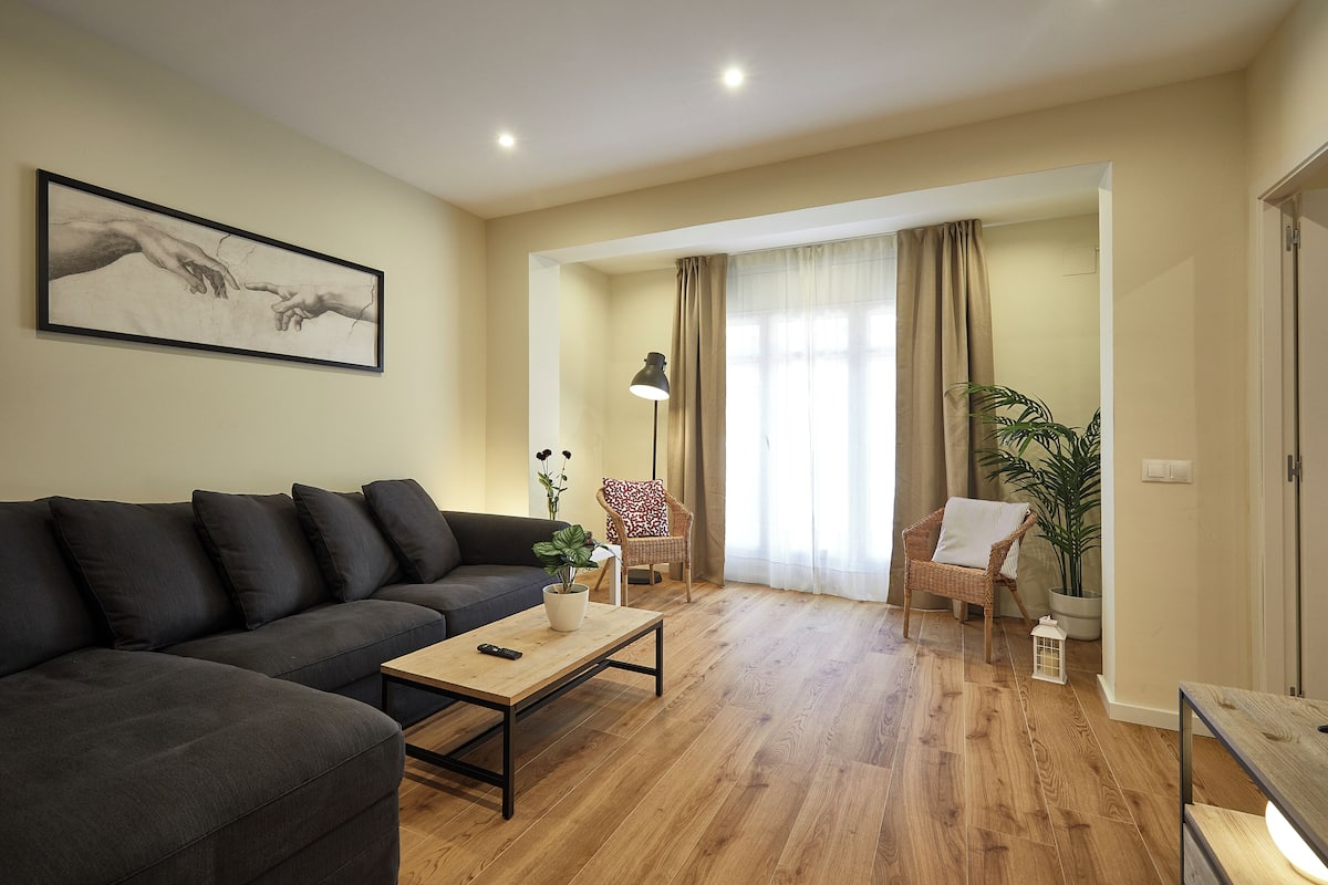 A modern living room with a dark grey sofa, a wooden coffee table, and a framed artwork on the wall.
