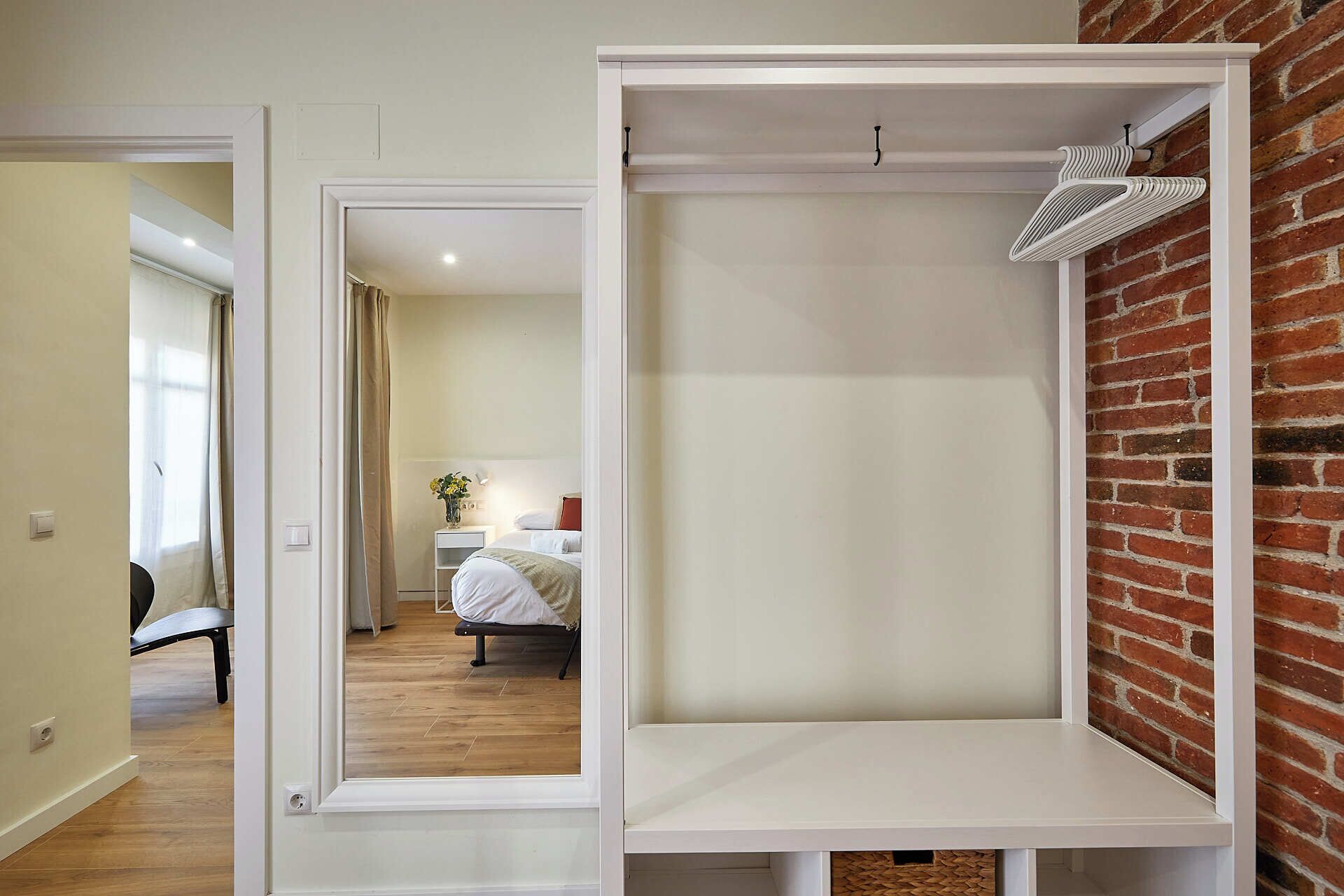 A hotel room with a bed, a bedside table with a lamp, and a brick wall.