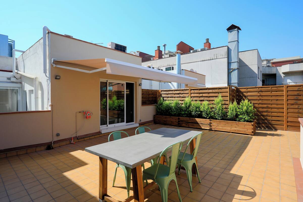 A patio with a table and chairs, a wooden fence, and a small garden area.