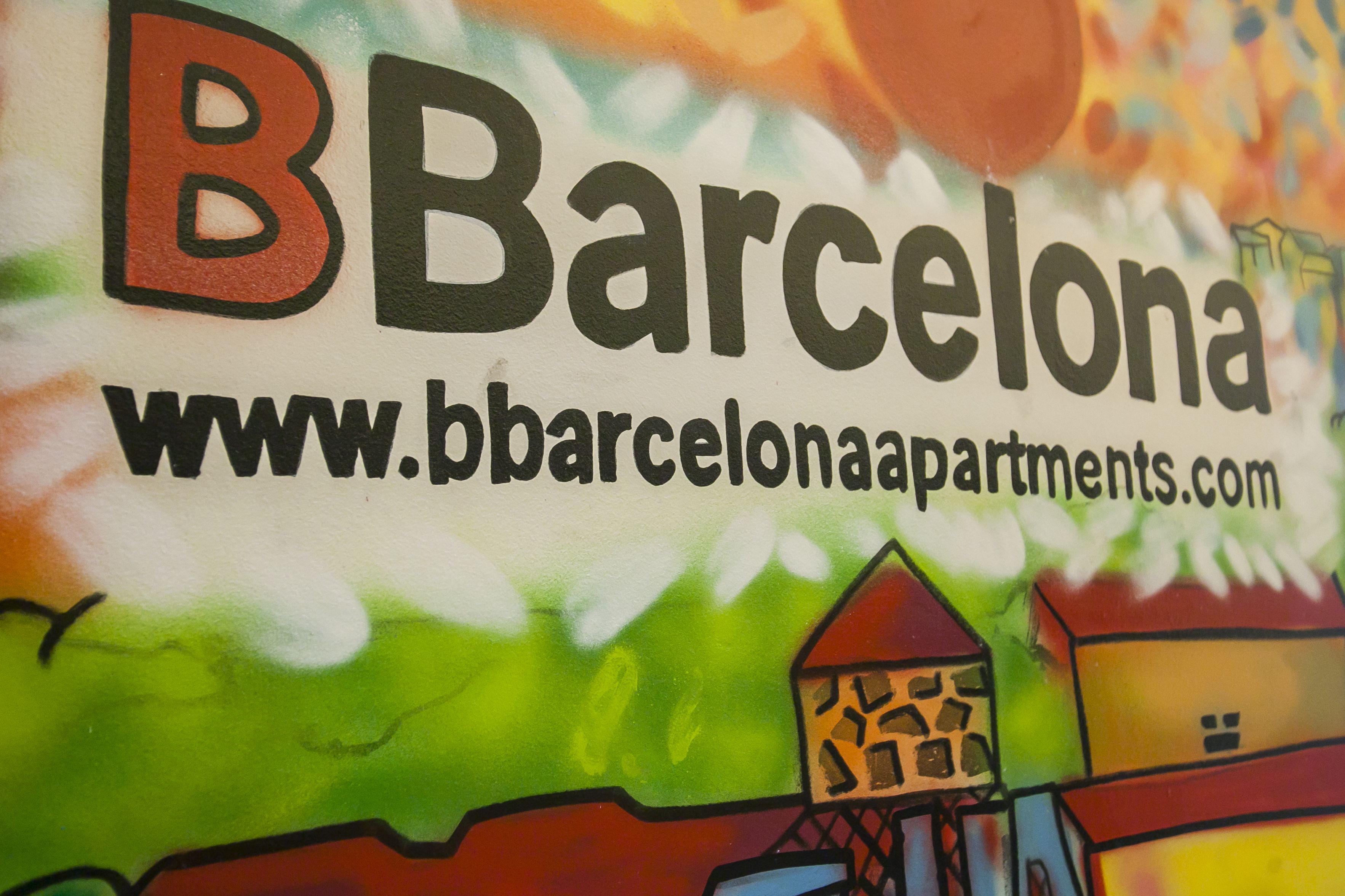 Une enseigne colorée portant l’inscription « Barcelone » et l’adresse d’un site web.