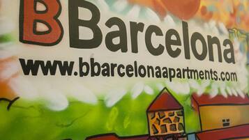Une enseigne colorée portant l’inscription « Barcelone » et l’adresse d’un site web.
