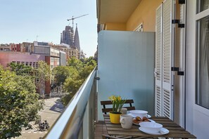 A balcony with a table set for breakfast, overlooking a cityscape with buildings and a construction crane. - Sagrada Familia Flats (Barcelona)