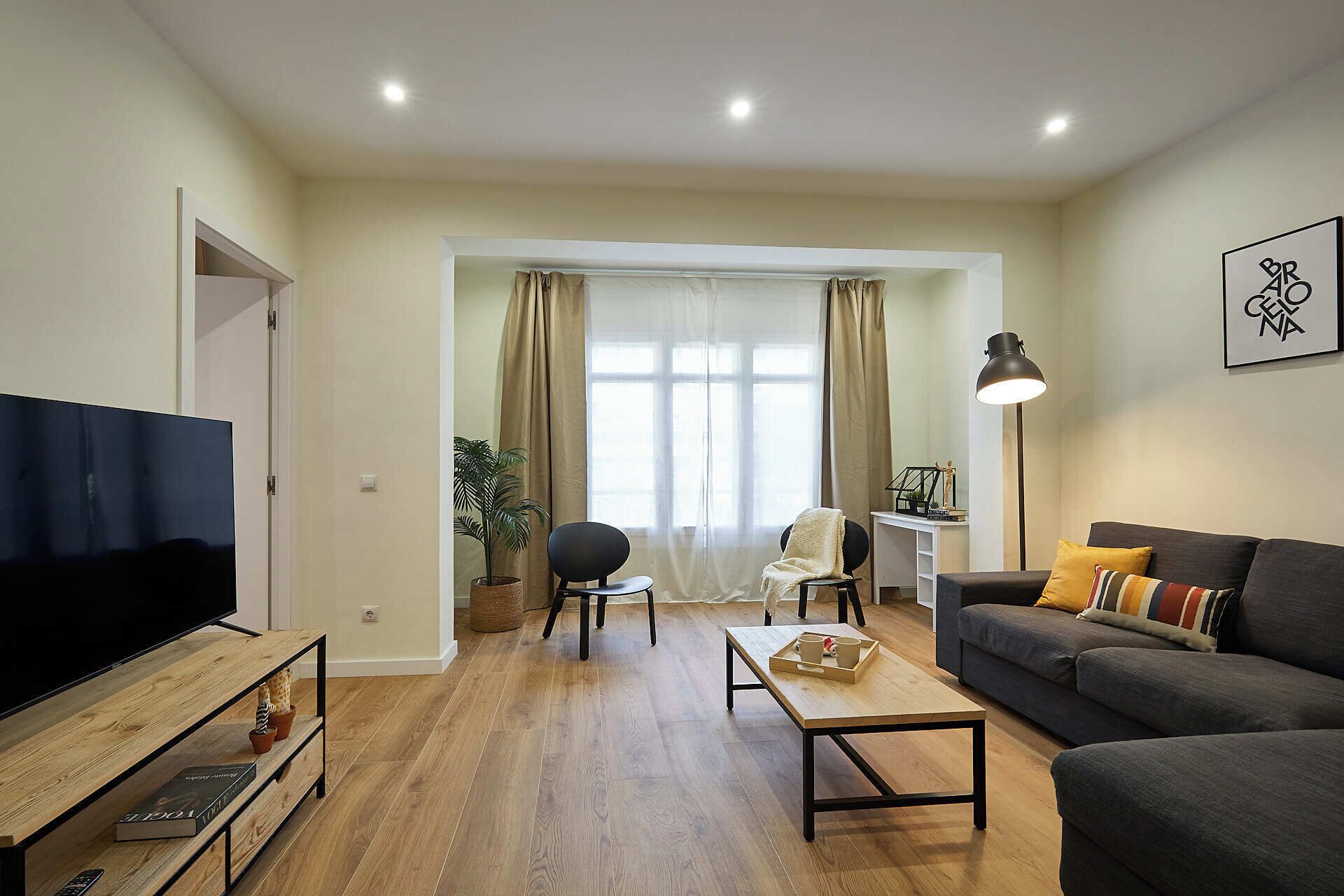 A living room with a TV, sofa, coffee table, and a lamp.