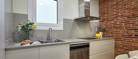 A modern kitchen with granite countertops, a stainless steel dishwasher, and a brick accent wall.