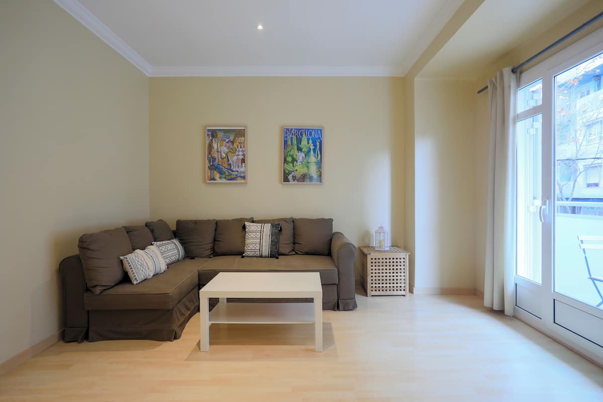 A living room with a brown sectional sofa, a white coffee table, and two paintings on the wall.