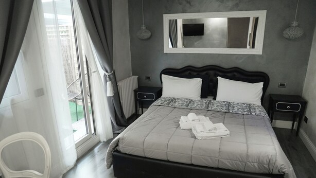 A bedroom with a bed, bedside tables, a mirror, and a view of the outside. - La Residenza Isabella (Milan)