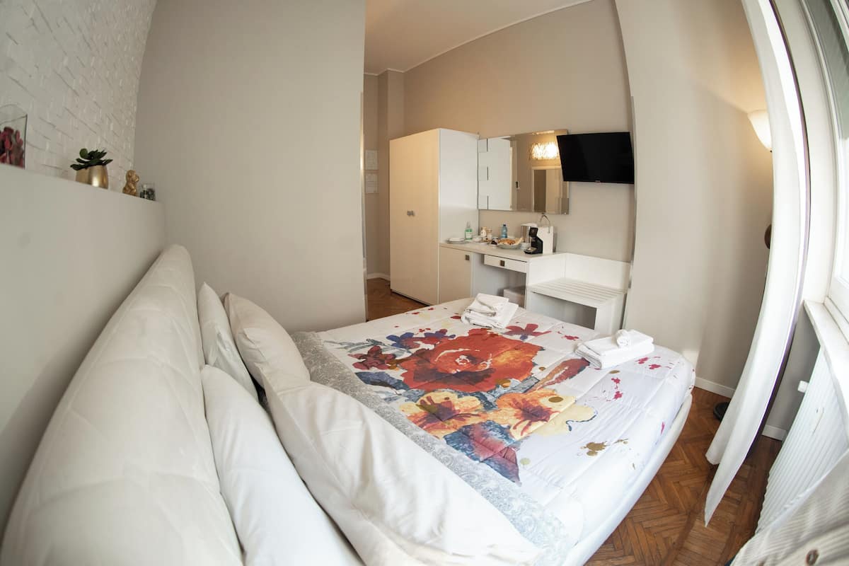 A bedroom with a bed, a dresser, a mirror, and a window.