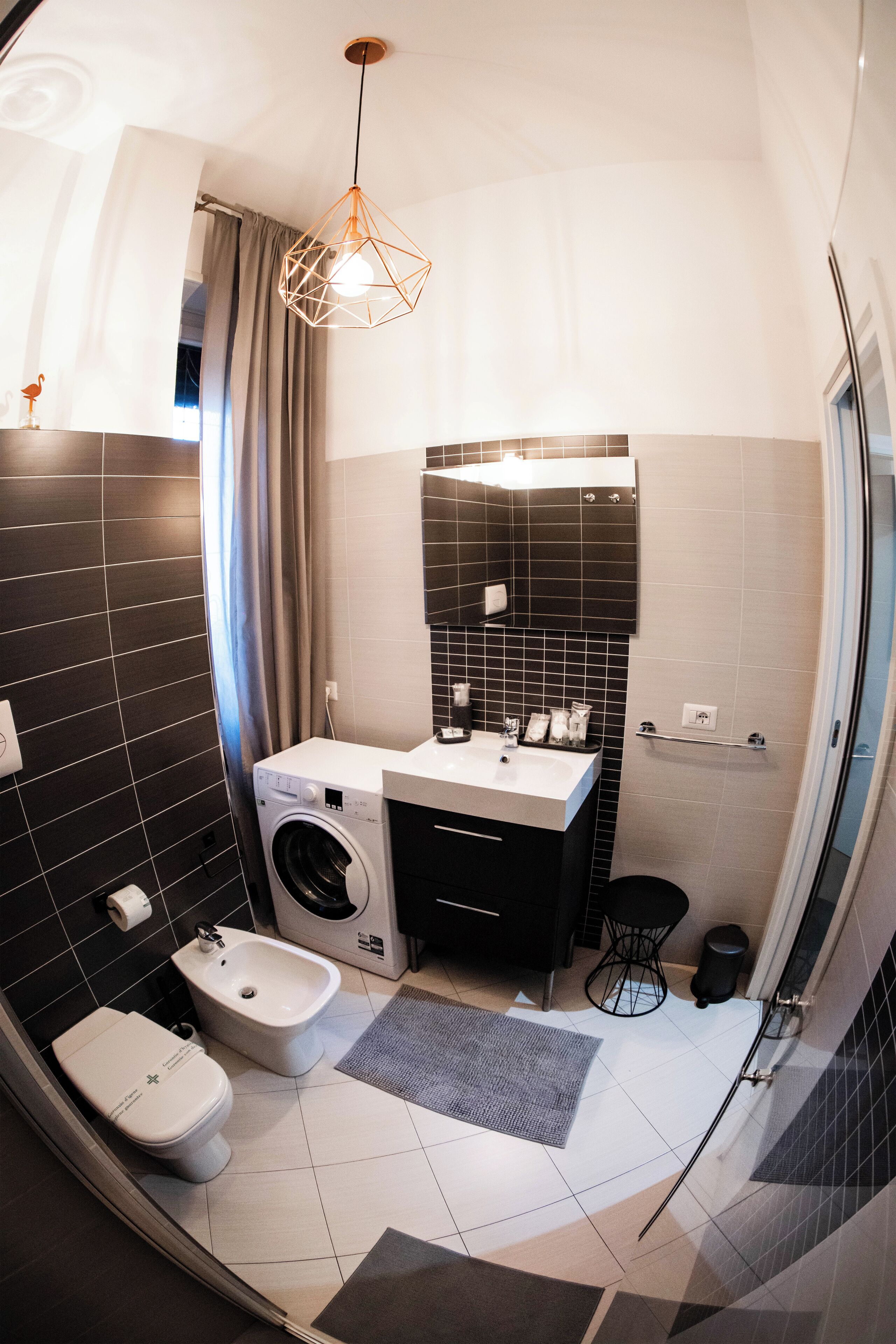 A compact bathroom with a washing machine, bidet, and modern fixtures.