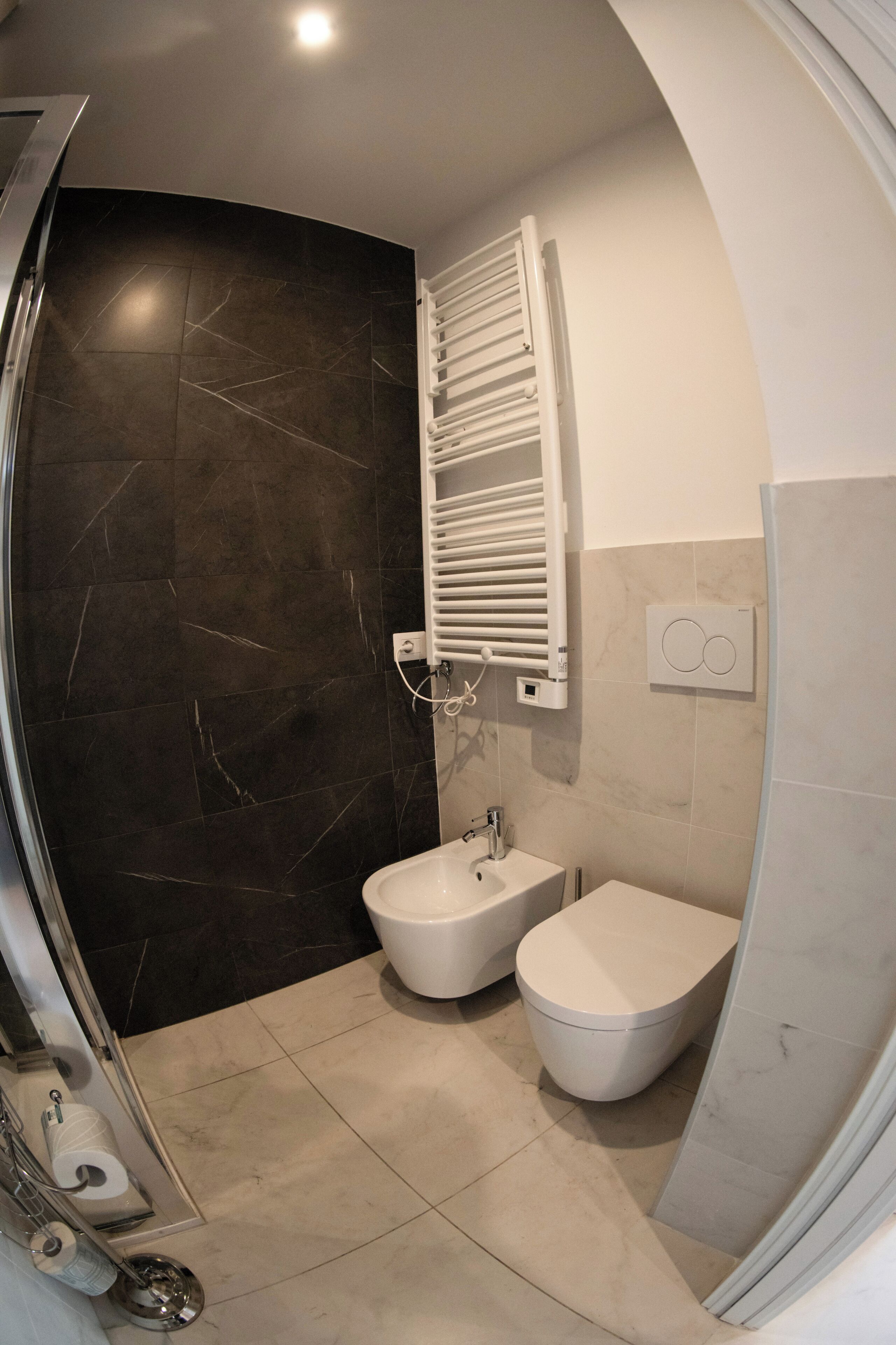 Een moderne badkamer met een hygiëneschuimer, toilet en douche.
