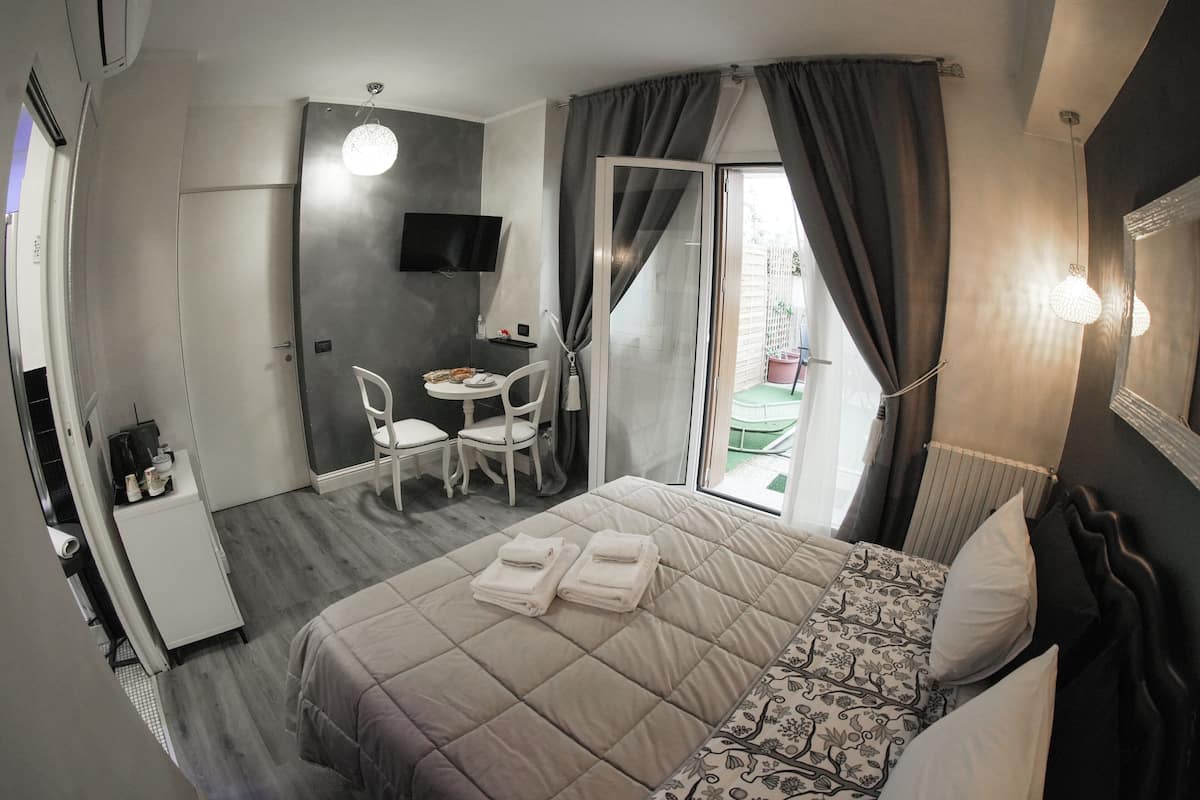 A hotel room with a bed, a desk with a chair, a television, and a view of the outside.