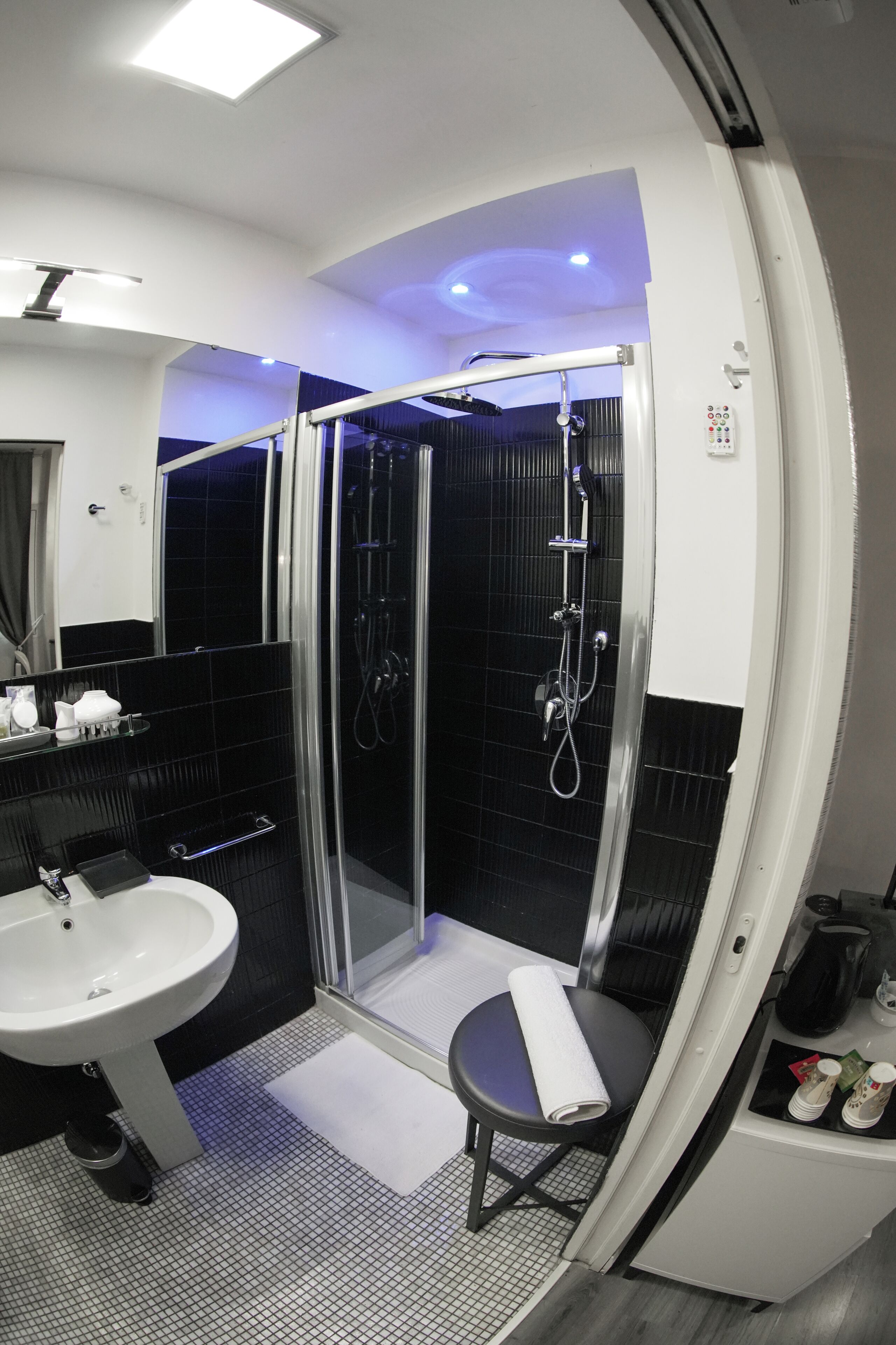 Une salle de bain moderne avec une douche à parois de verre, un lavabo et un petit coin salon.