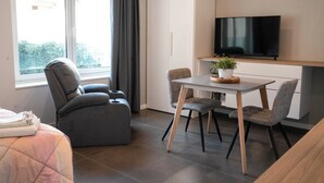 A modern hotel room with a bed, a seating area with a table and chairs, a flat-screen TV mounted on the wall, and a window with curtains. - La Residenza Isabella (Milan)