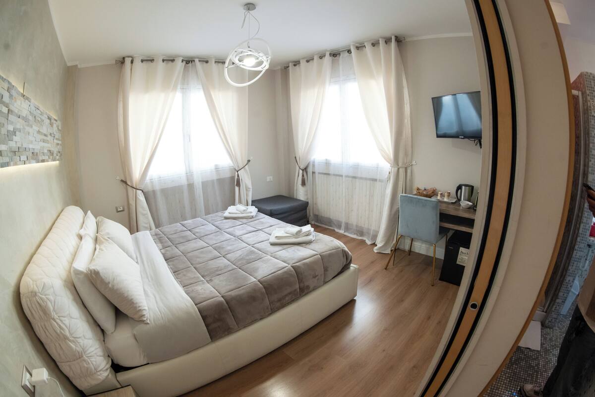 A modern bedroom with a bed, a desk, and a TV.