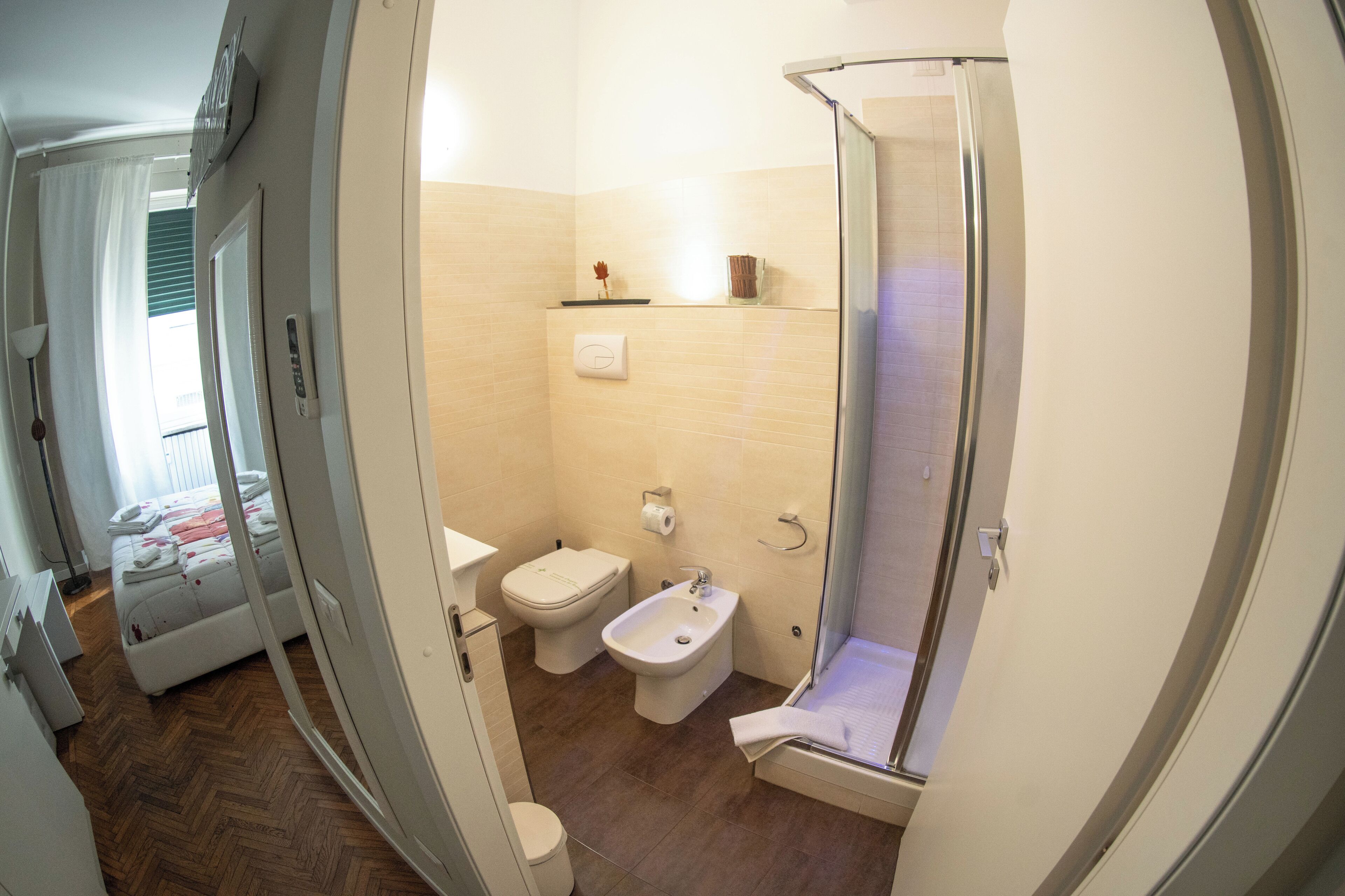 A bathroom with a shower, toilet, bidet, and a small shelf with toiletries.
