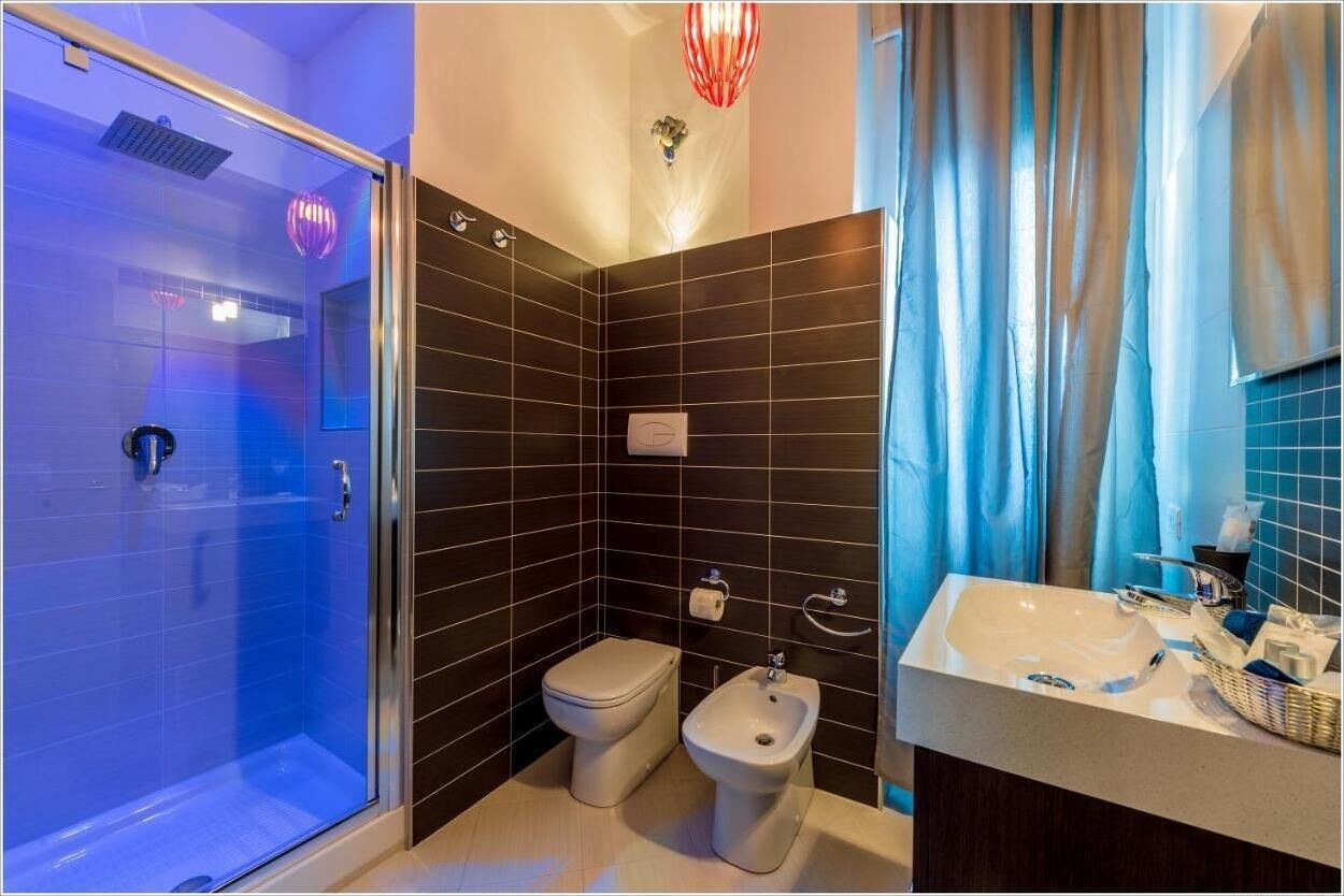 A bathroom with a glass shower enclosure, a toilet, a bidet, and a sink with a mirror.
