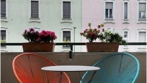 A balcony with two chairs and a table, overlooking a row of pastel-colored buildings. - La Residenza Isabella (Milan)