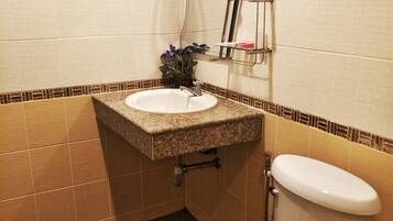 A bathroom with a white sink, a toilet, and a shower area.