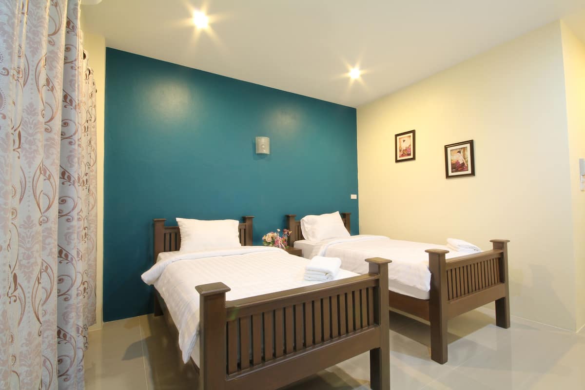 A bedroom with two wooden beds, a teal accent wall, and a white ceiling.