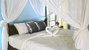 A bed with a canopy, pillows, and a swan-shaped bedspread. - Blue House Sukhothai (Sukhothai)