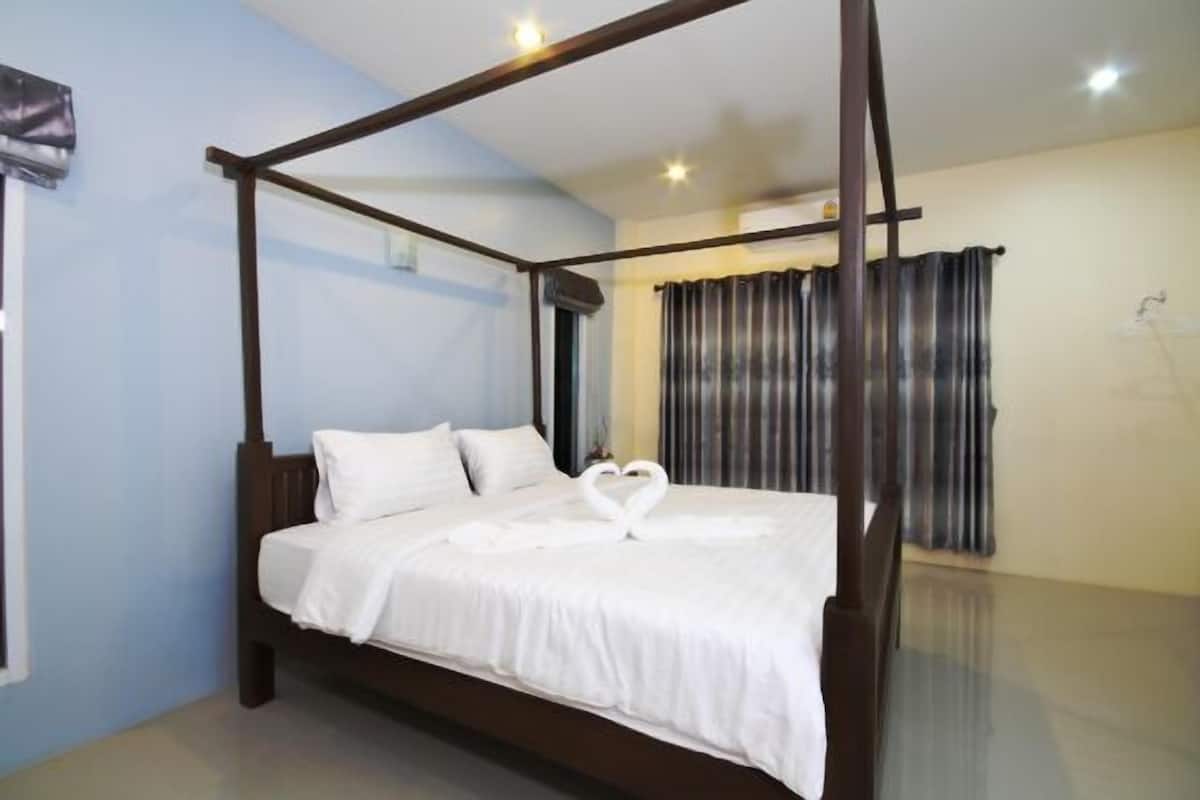 A four-poster bed with white linens and a heart-shaped towel arrangement.