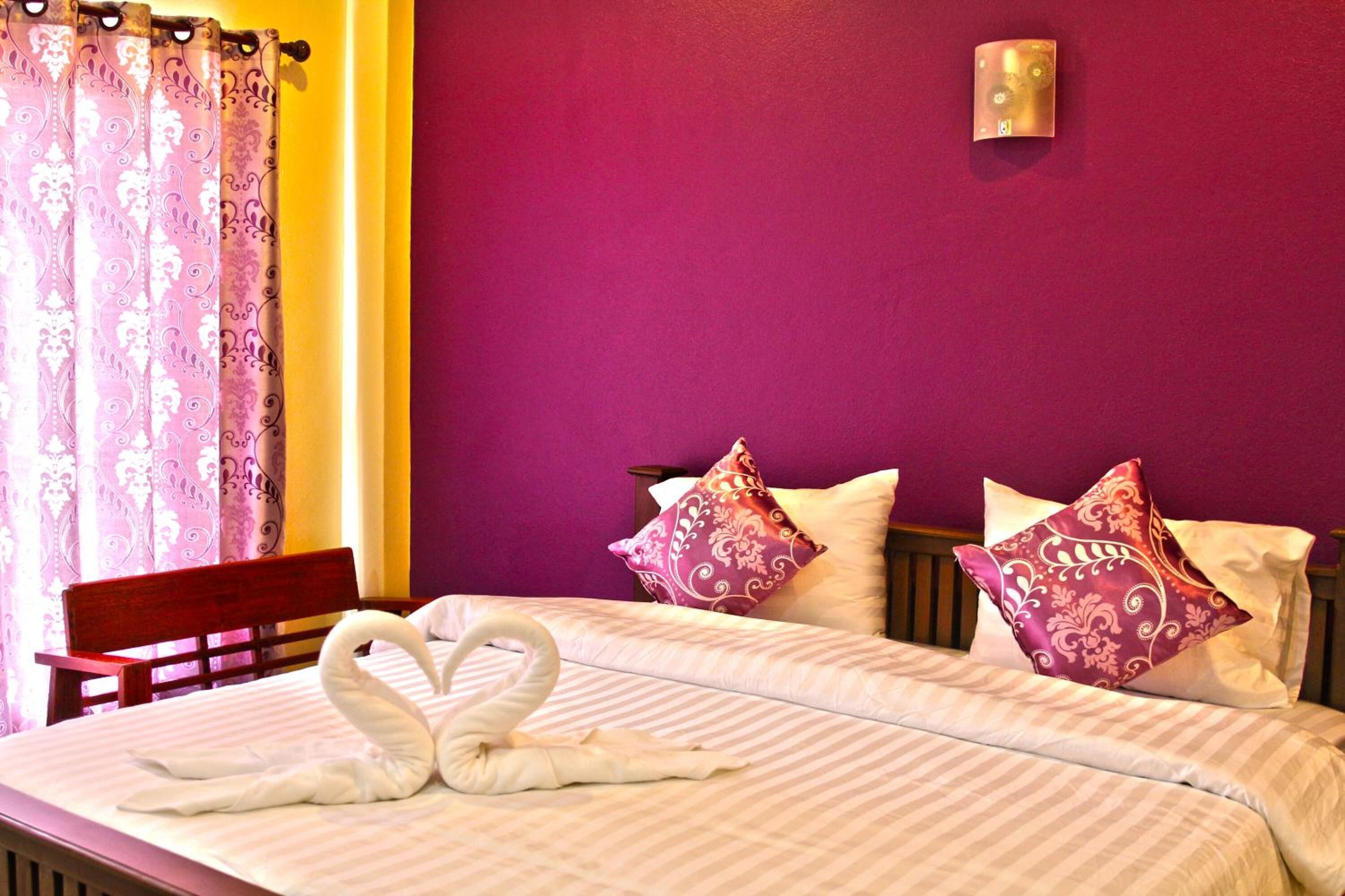 A hotel room with a bed, pillows, and a swan-shaped towel arrangement.