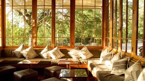 A room with large windows, a wooden bench, and cushioned seating. - Termas Jahuel Hotel & Spa (Santa Maria)