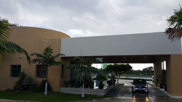 A modern building with a curved facade, a covered entrance, and a paved driveway.
