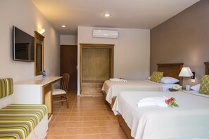 A hotel room with two beds, a desk, a chair, a TV, and an air conditioning unit.