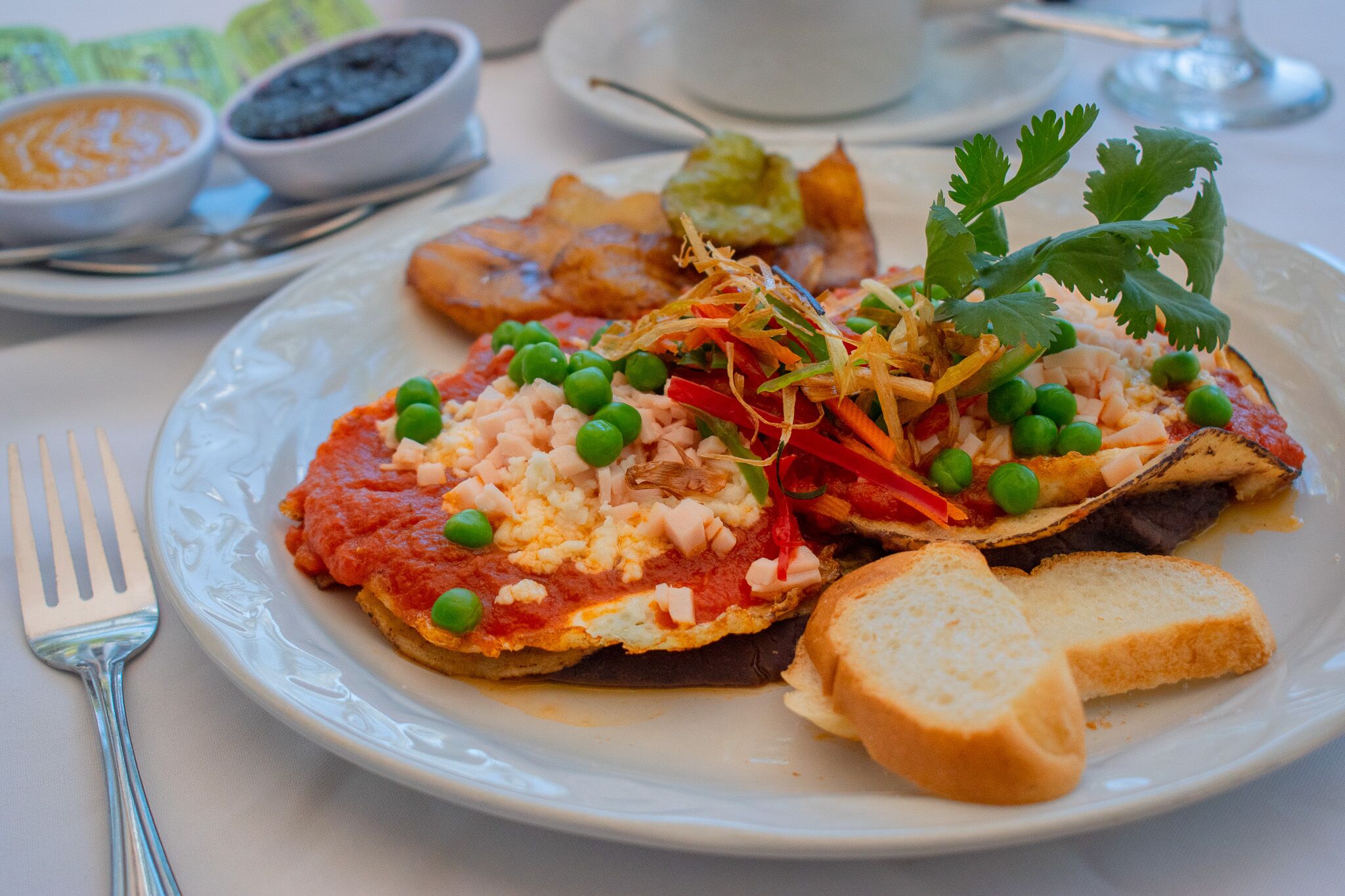 A plate of food with various toppings including peas, carrots, and a piece of bread.