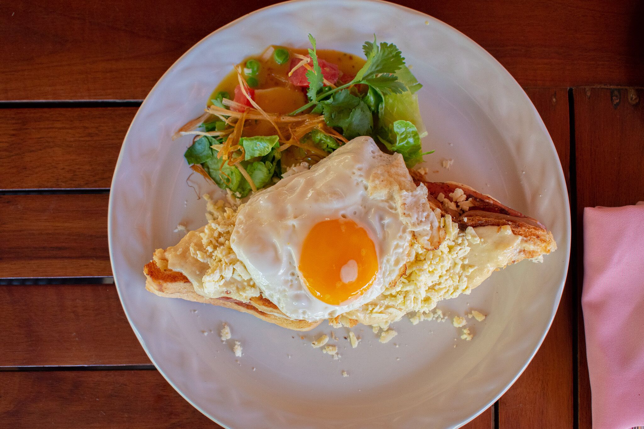 A plate with a fried egg, a piece of bread, and a salad.