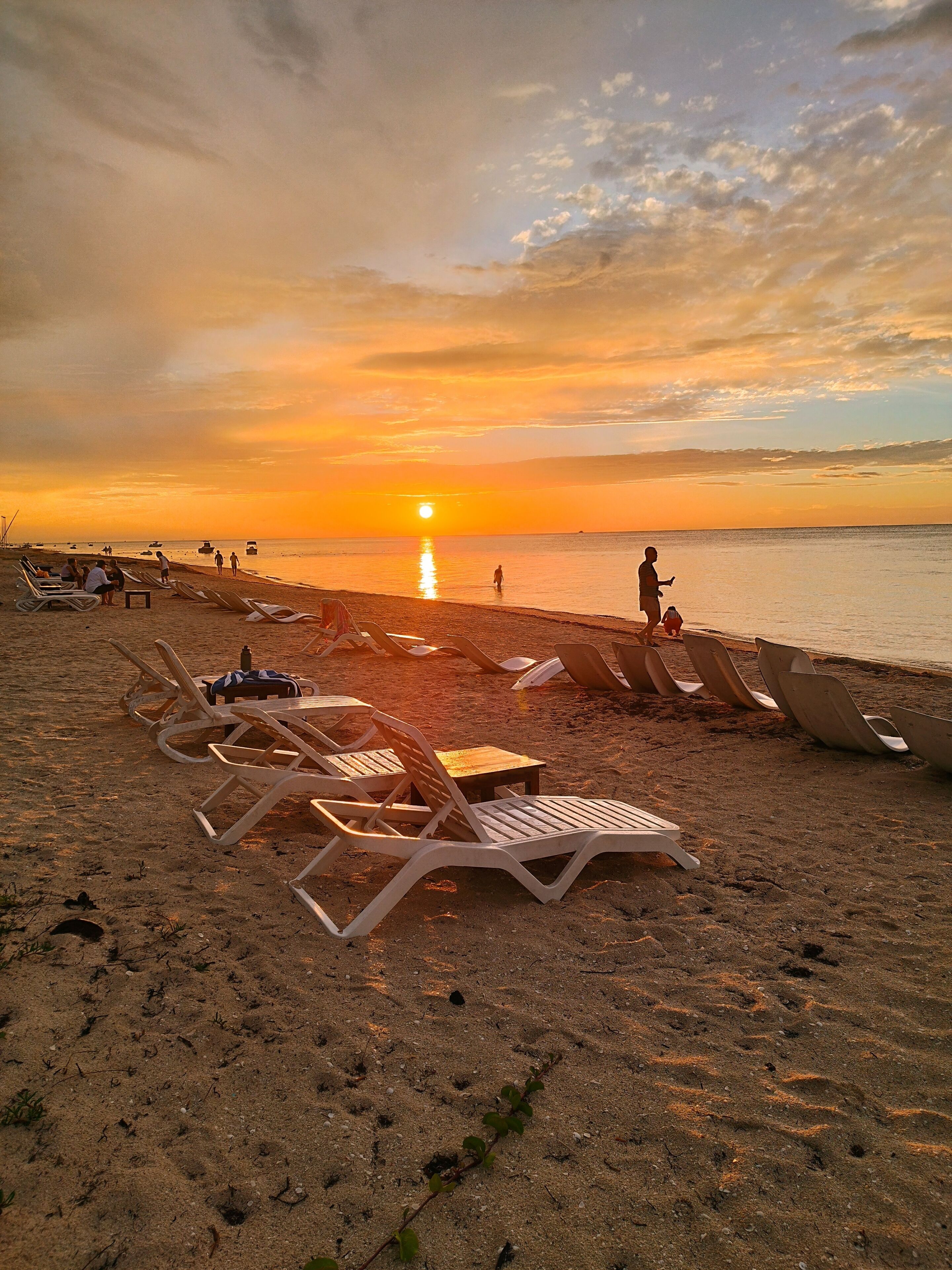 Una playa con tumbonas y un atardecer.