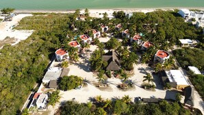 Vista aérea de un resort con varias edificaciones, palmeras y una playa.