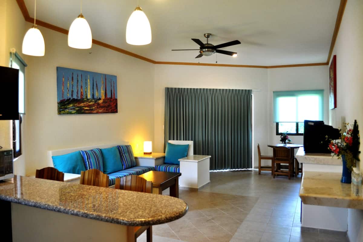A modern living room with a sofa, a coffee table, a TV, and a ceiling fan.