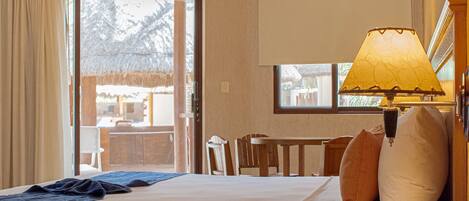Une chambre d’hôtel avec un lit, une table de chevet avec une lampe, un téléphone et une vue sur l’extérieur par une fenêtre.