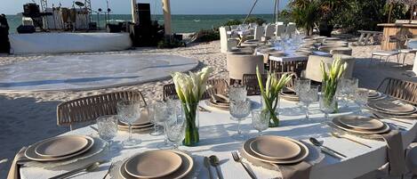 An outdoor dining area with tables set for a meal, overlooking the sea.
