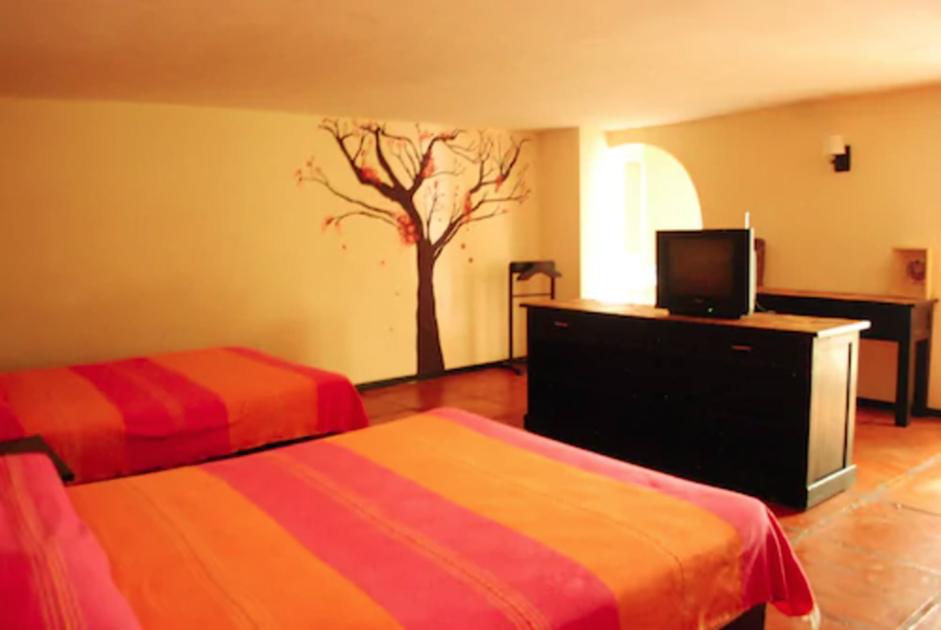 A room with two beds, a TV, and a dresser.
