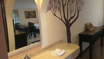 A bathroom with a sink, mirror, and a tree decal on the wall.