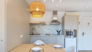 A modern kitchen with a marble countertop, a built-in microwave, and a stainless steel range hood. - Martinez Apartments (Calvia)