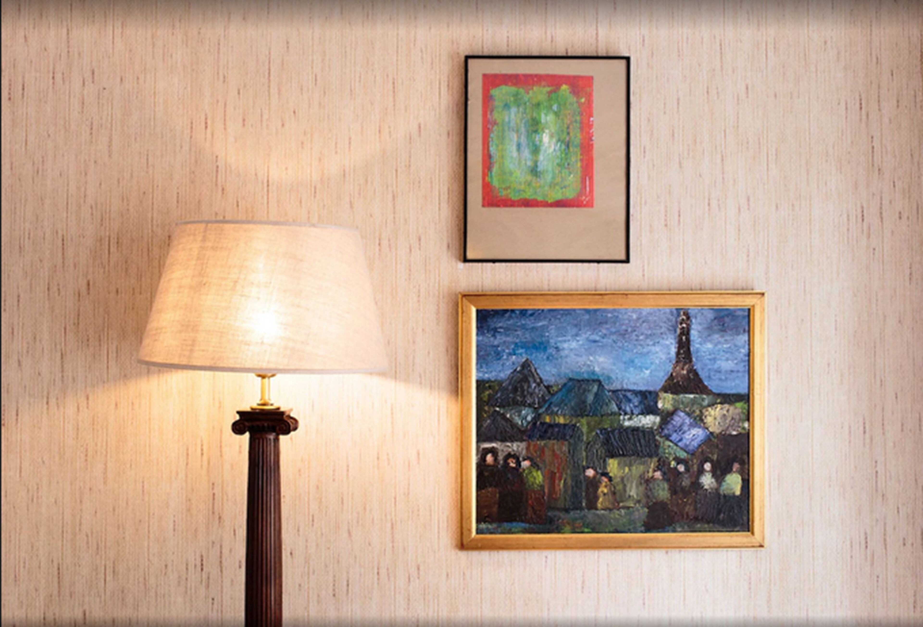 A lamp and two framed artworks on a wall.