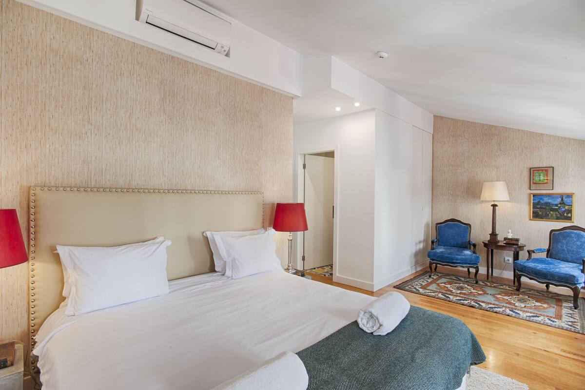 Habitación de hotel con una cama grande, dos sillas, una mesita y una alfombra.