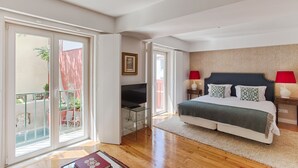 Un dormitorio con cama, televisión, balcón y vistas al exterior.