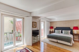 Quarto com cama, televisão, varanda e vista para o exterior.